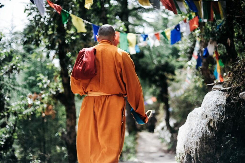Unrecognizable Buddhist monk in green garden